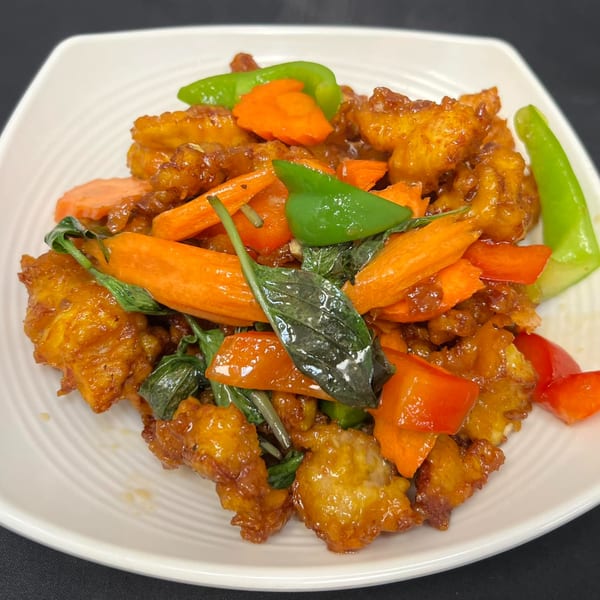 Tuk Tuk Thai Campbell's crispy chicken stir-fry with carrots, bell peppers, and basil on a white plate.